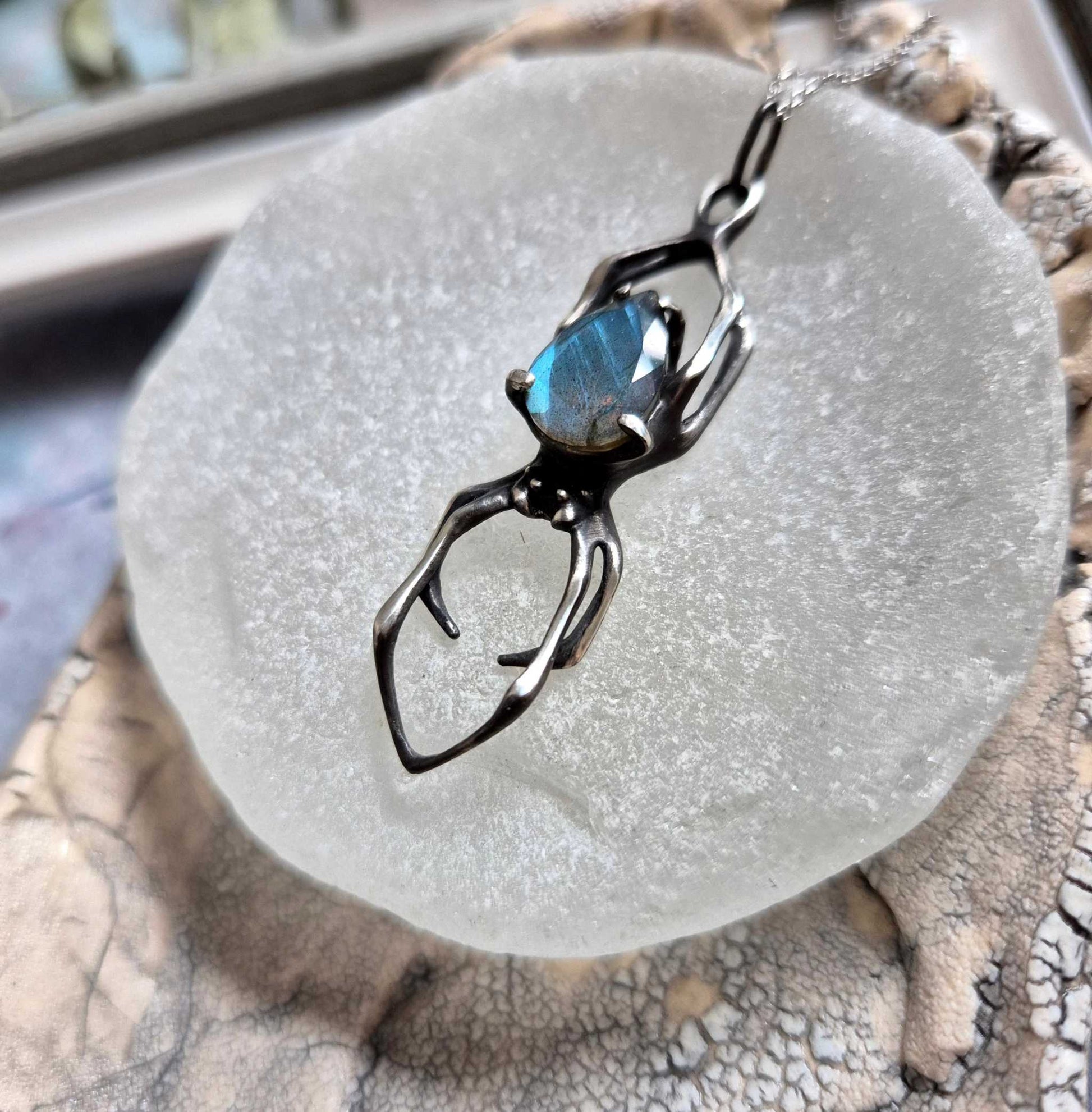 Oxidized silver Spider pendant with blue labradorite, resting on matte glass surface
