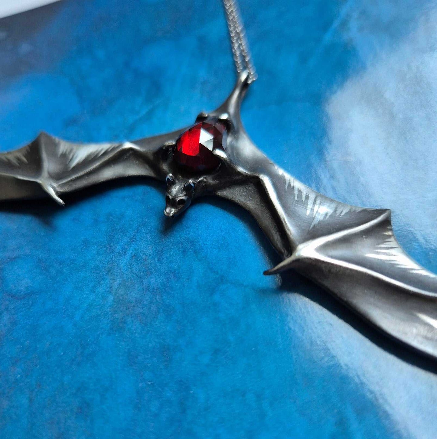 Silver Bat necklace - Natural Garnet - Handmade symbolic jewelry on blue paper