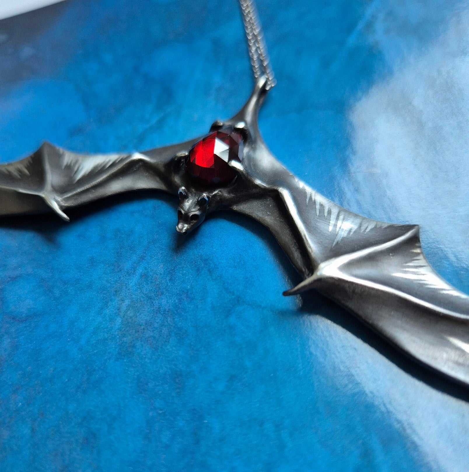 Silver Bat necklace - Natural Garnet - Handmade symbolic jewelry on blue paper