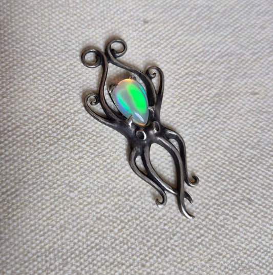 Silver Octopus necklace with natural opal — textured tentacles and vivid opal fire on a ceramic background.