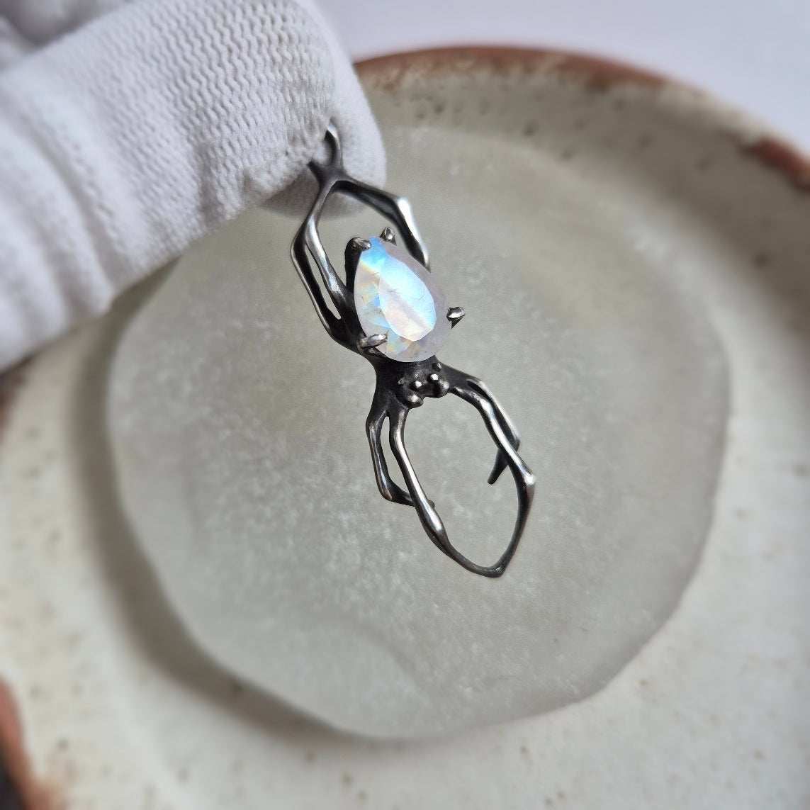 Close-up of silver Spider necklace with glowing rainbow moonstone cabochon