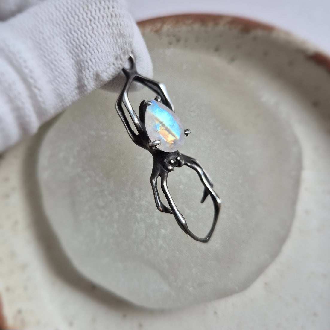 Handmade silver Spider necklace with iridescent moonstone gemstone on light background