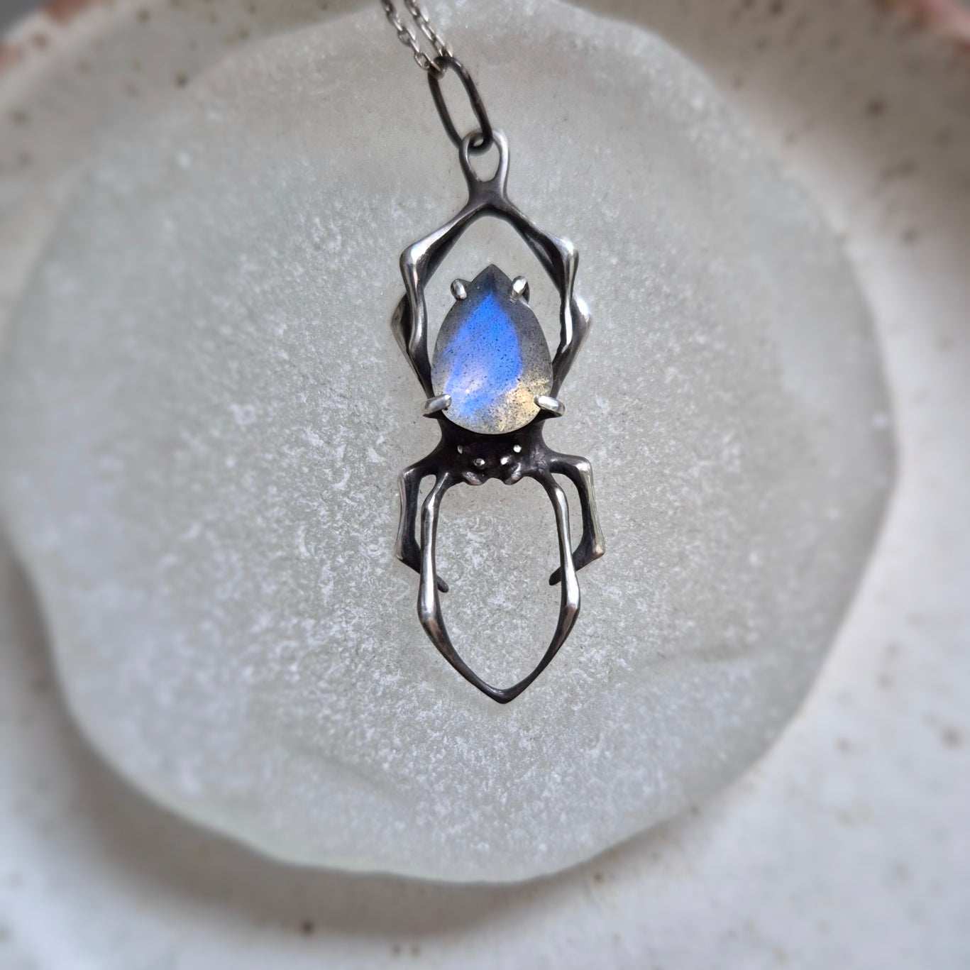 Close-up of handmade oxidised silver spider necklace with natural gemstone