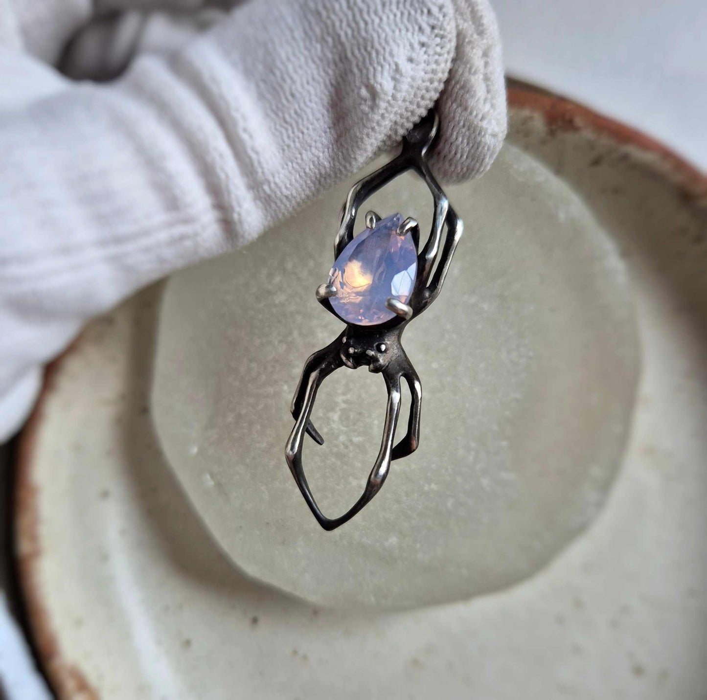 Silver spider necklace with lavender quartz gemstone on ceramic dish, handmade oxidized pendant