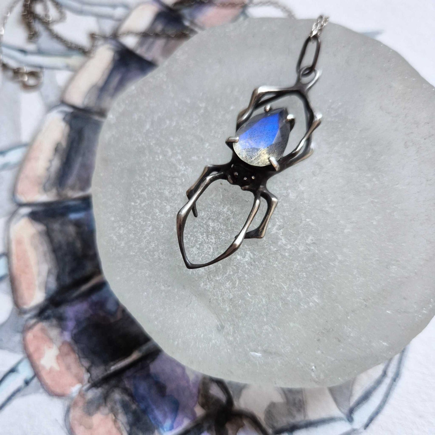 Creation Spider talisman on blurry background on watercolor