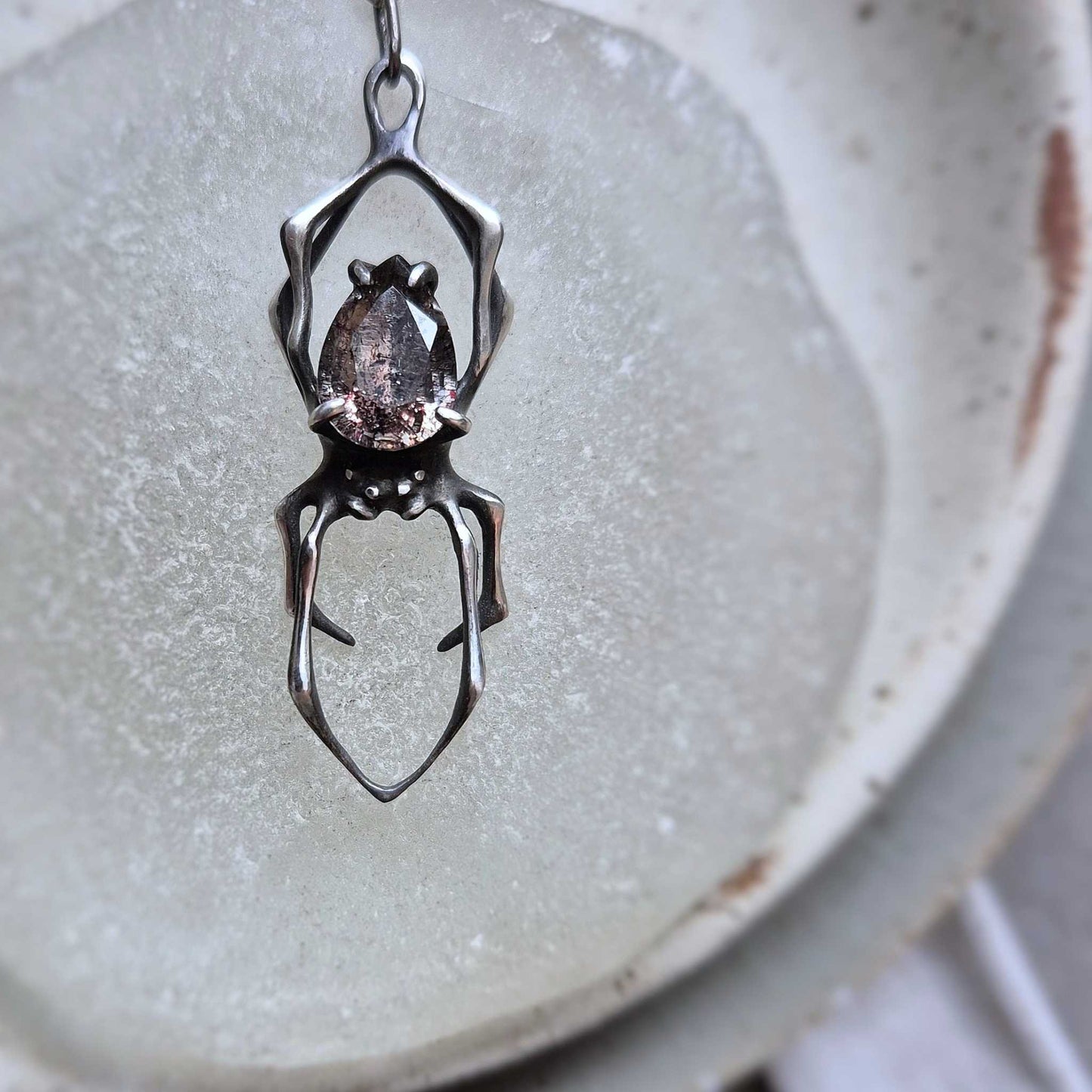 Close-up of oxidized silver Spider necklace featuring Super Seven quartz gem