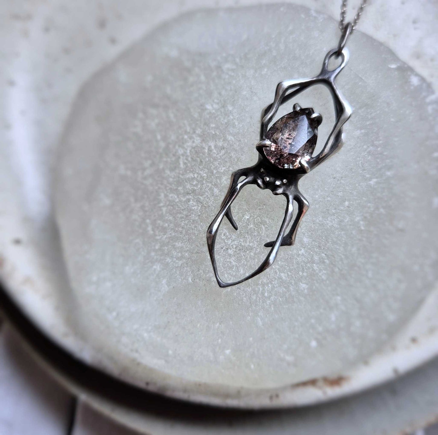 Close-up Silver Spider necklace styled on pale background with visible gemstone pattern