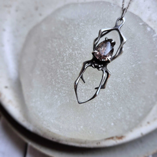 Close-up Silver Spider necklace styled on pale background with visible gemstone pattern