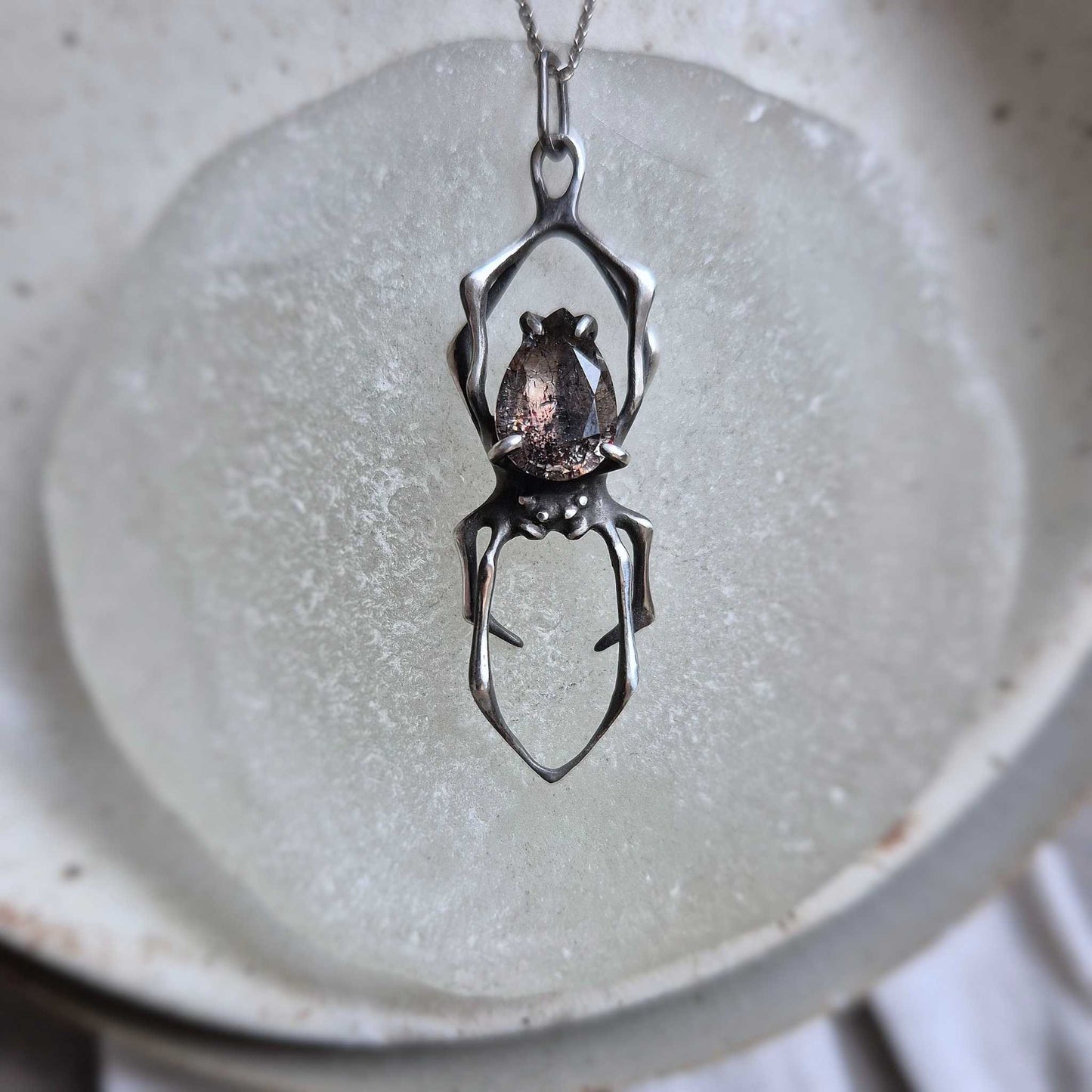 Artistic shot of silver Spider necklace with Super Seven crystal, gothic style jewelrySterling silver Spider necklace with dark Super Seven gem, handmade jewelry photo