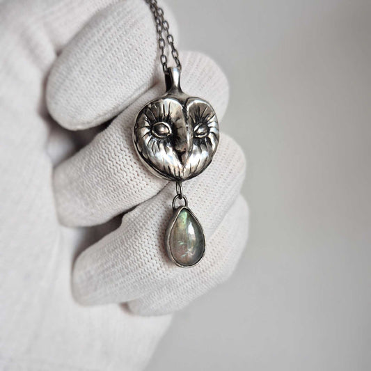 Side view of silver Owl necklace showing the gentle curve of the Barn owl face and the labradorite droplet