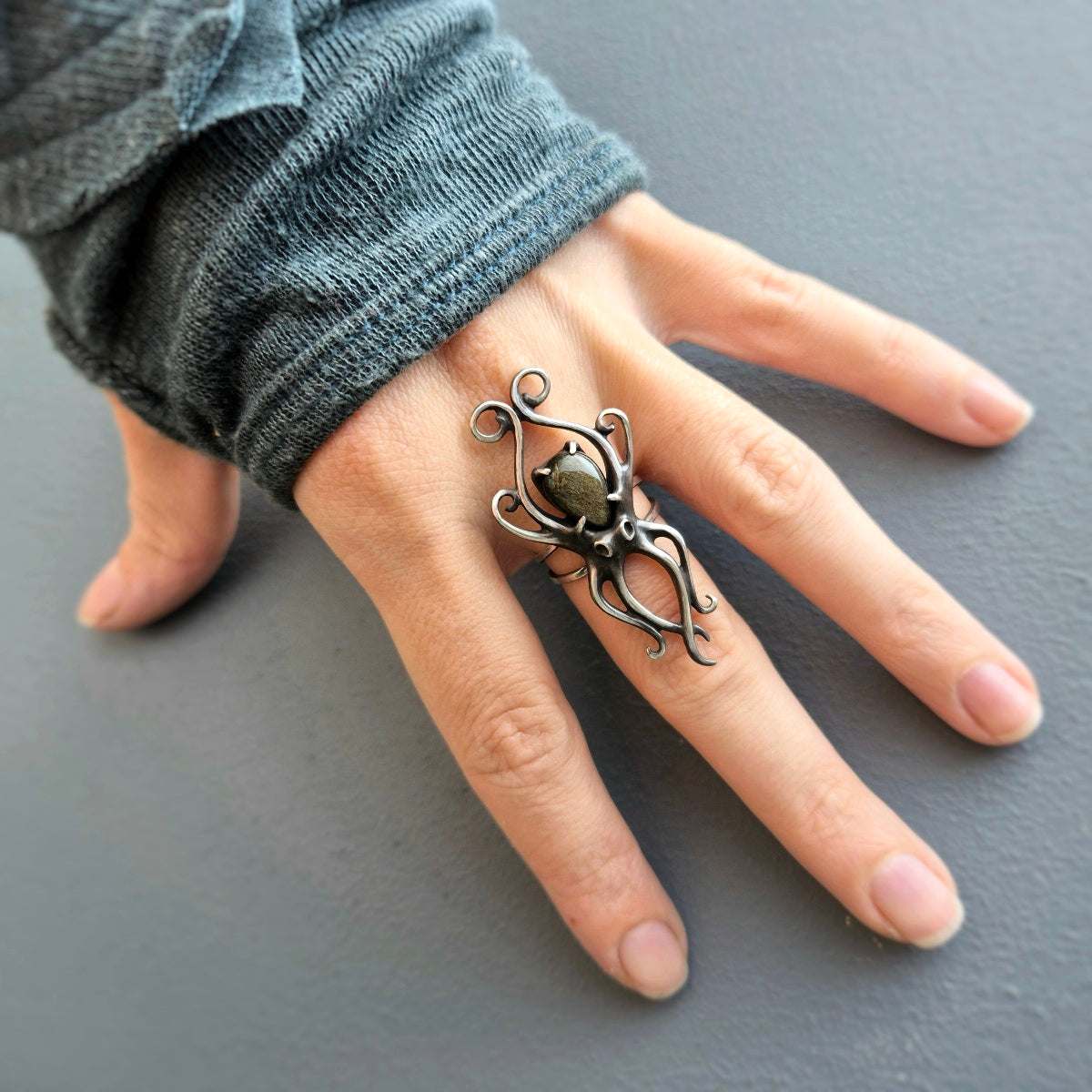 Elegant roughly-textured ring featuring an Octopus design and gold-sheened obsidian, captured from side angle