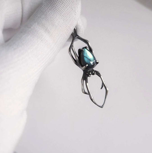 Close-up silver spider necklace with labradorite, held between fingers