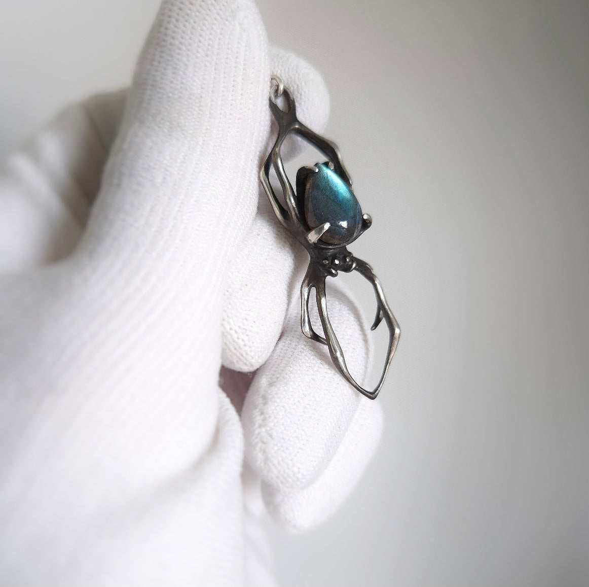 Detailed view of silver spider necklace with cyan labradorite cabochon, handcrafted in oxidised sterling silver
