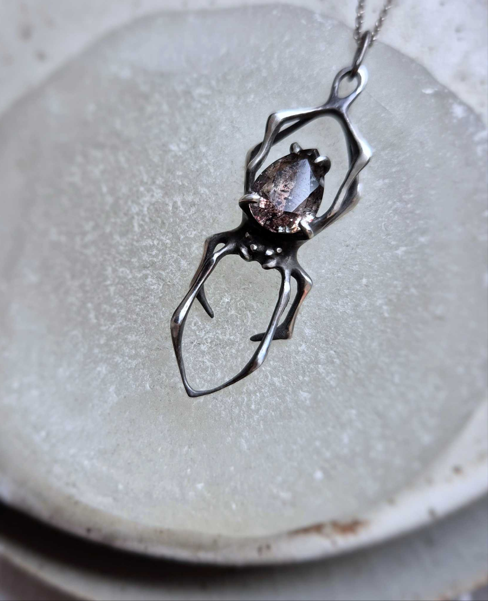 Handmade silver Spider necklace with natural Super Seven gemstone on matte background