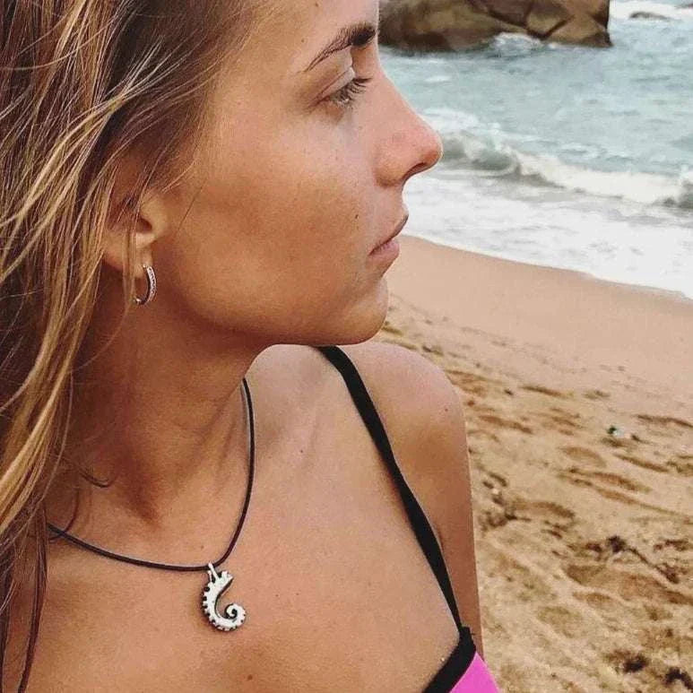 Woman wearing the necklace, gazing toward the sea on a windy day.