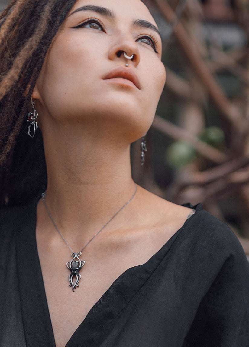 Witchy model in nature setting wearing oxidized silver octopus necklace with labradorite gem