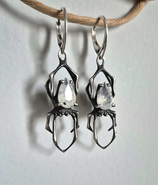 Handcrafted silver Spider earrings hanging on cord, shown front view