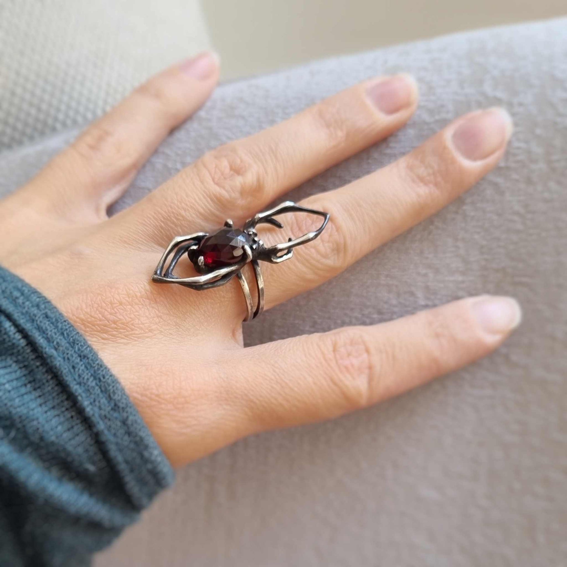 Side view of silver Spider ring with rose-cut garnet, highlighting the arched legs and dual band