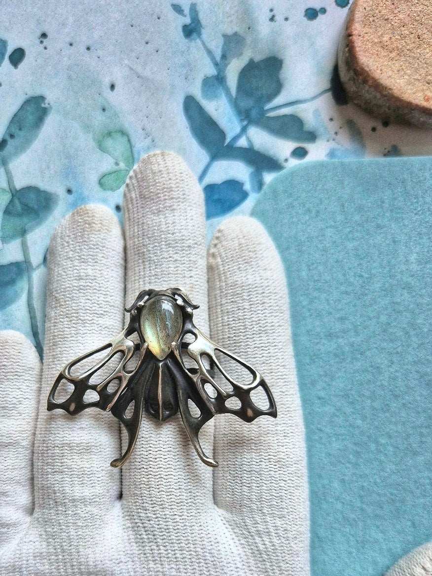 Detailed silver Moth ring with silvery labradorite shown on white glove, handcrafted fantasy jewelry
