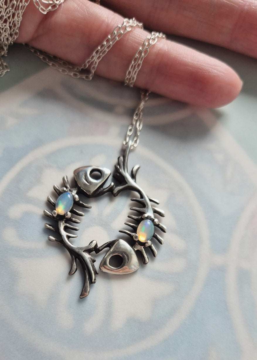 Silver fish skeleton necklace with two Ethiopian opals on patterned background