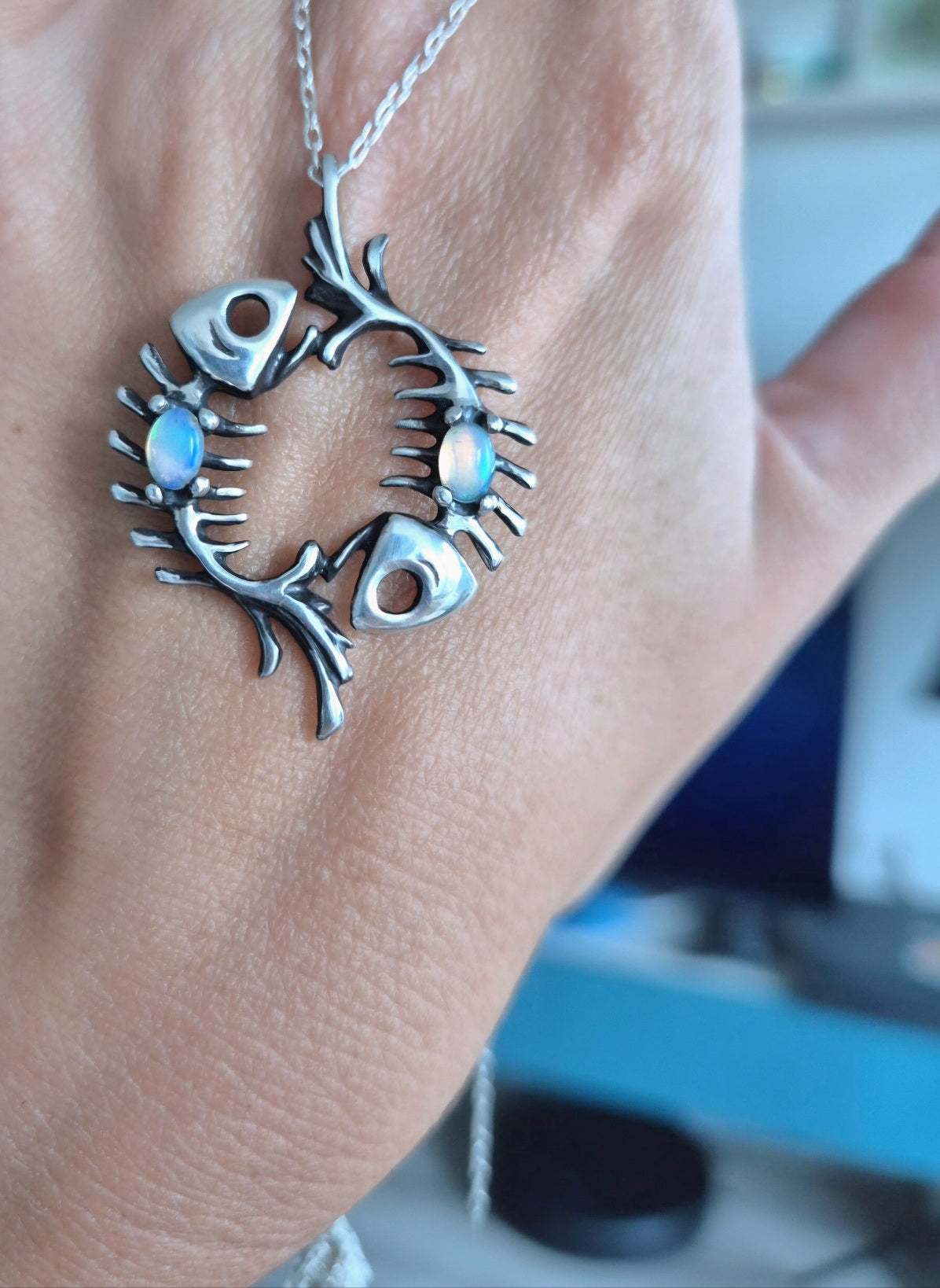 Handmade fish necklace featuring skeletal fish forms and glowing opals