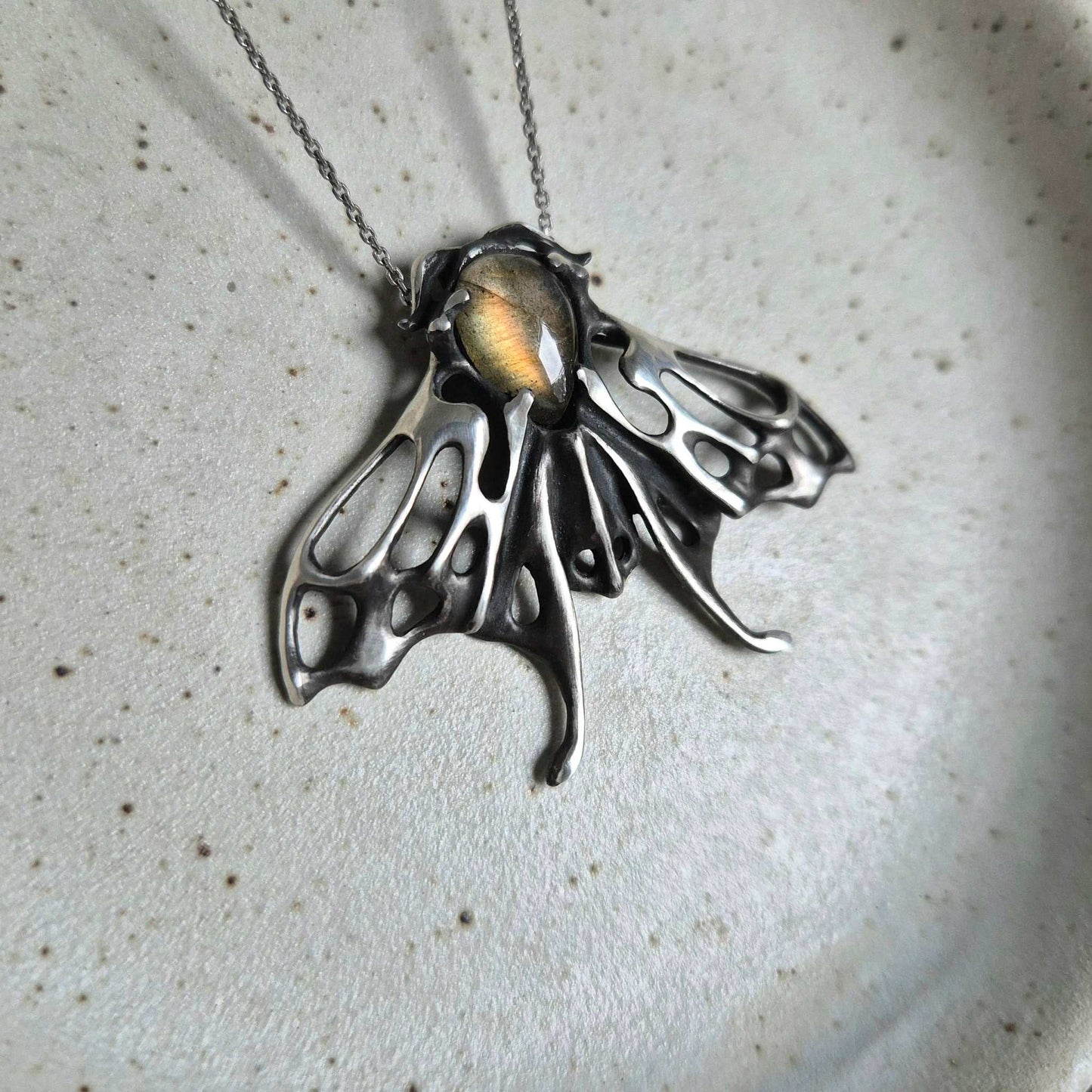 Handmade silver Moth necklace with warm golden labradorite cabochon, side view