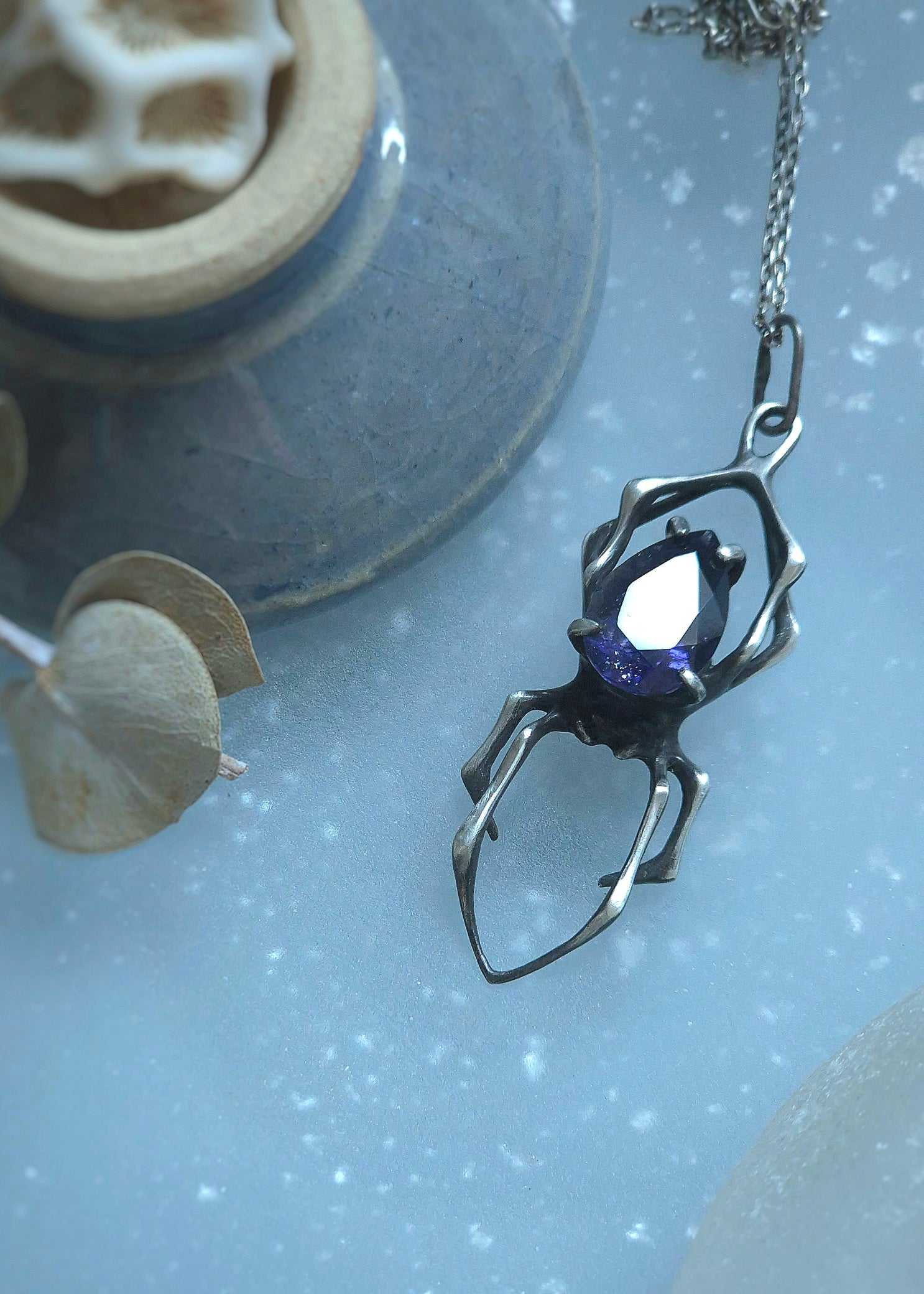 Close-up of handmade oxidised silver spider necklace with natural gemstone