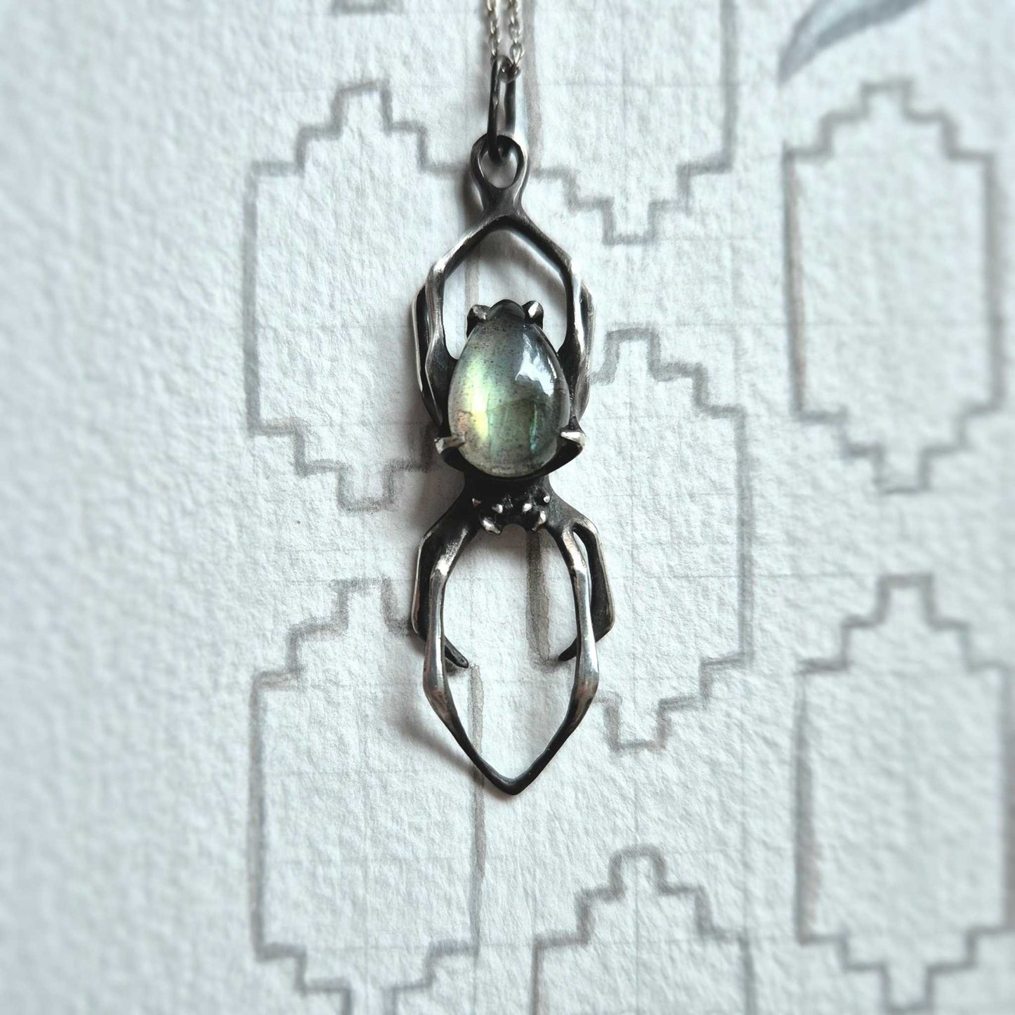 Silver Spider necklace with labradorite gemstone photographed on geometric white background