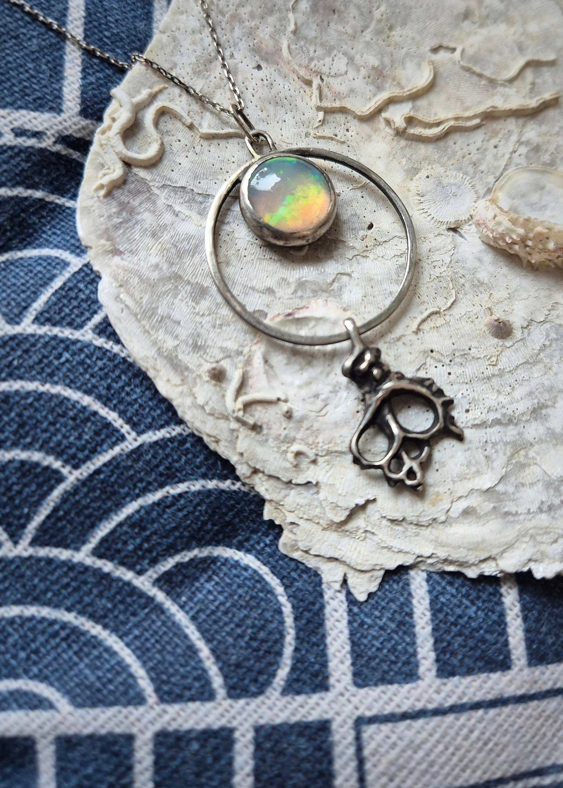 Ethereal opal pendant necklace with silver shell drop — handmade ocean-inspired jewelry displayed on a seashell on blue fabric