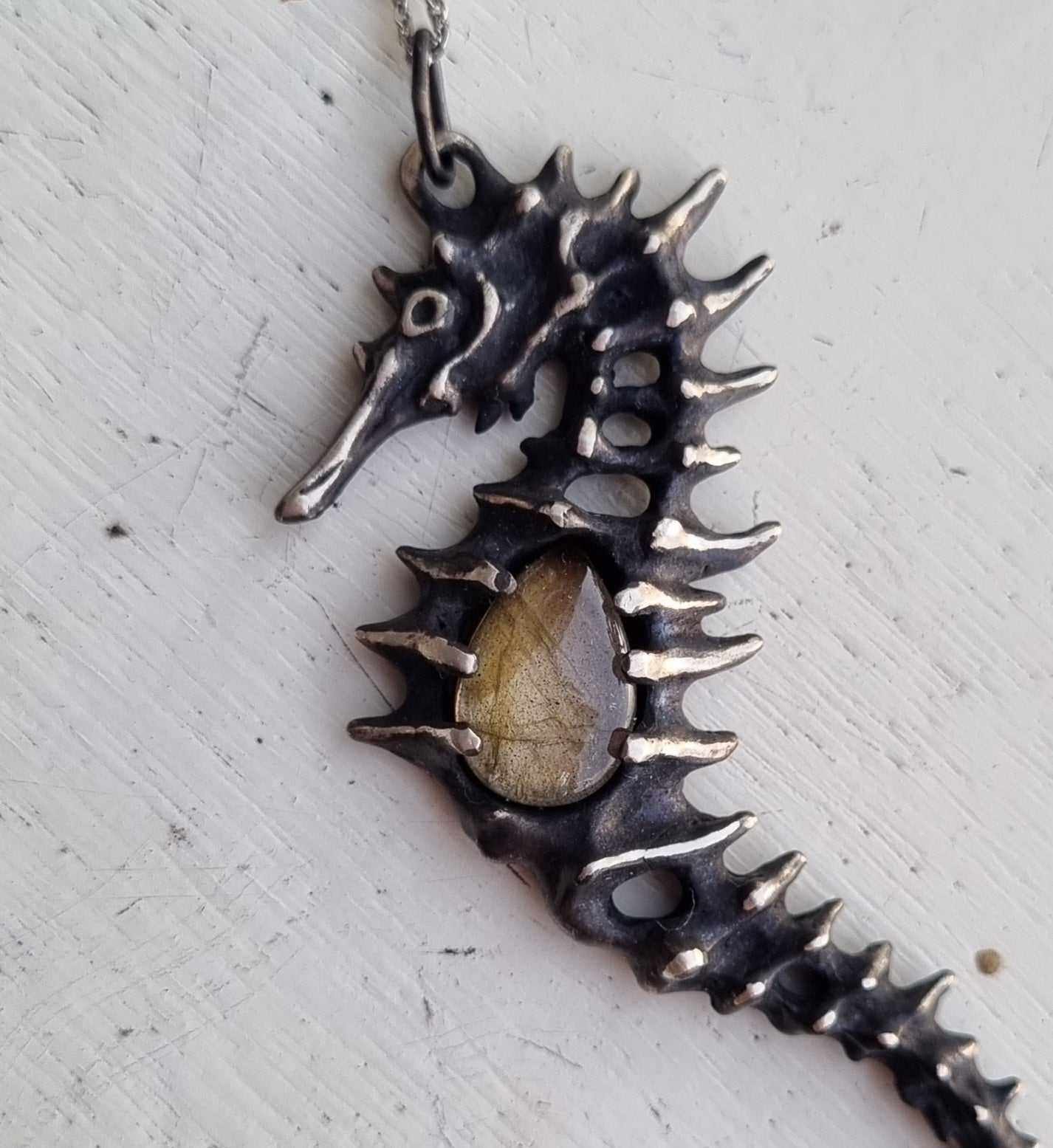 Close-up of a Silver Seahorse necklace featuring a striped labradorite, displayed on neutral background