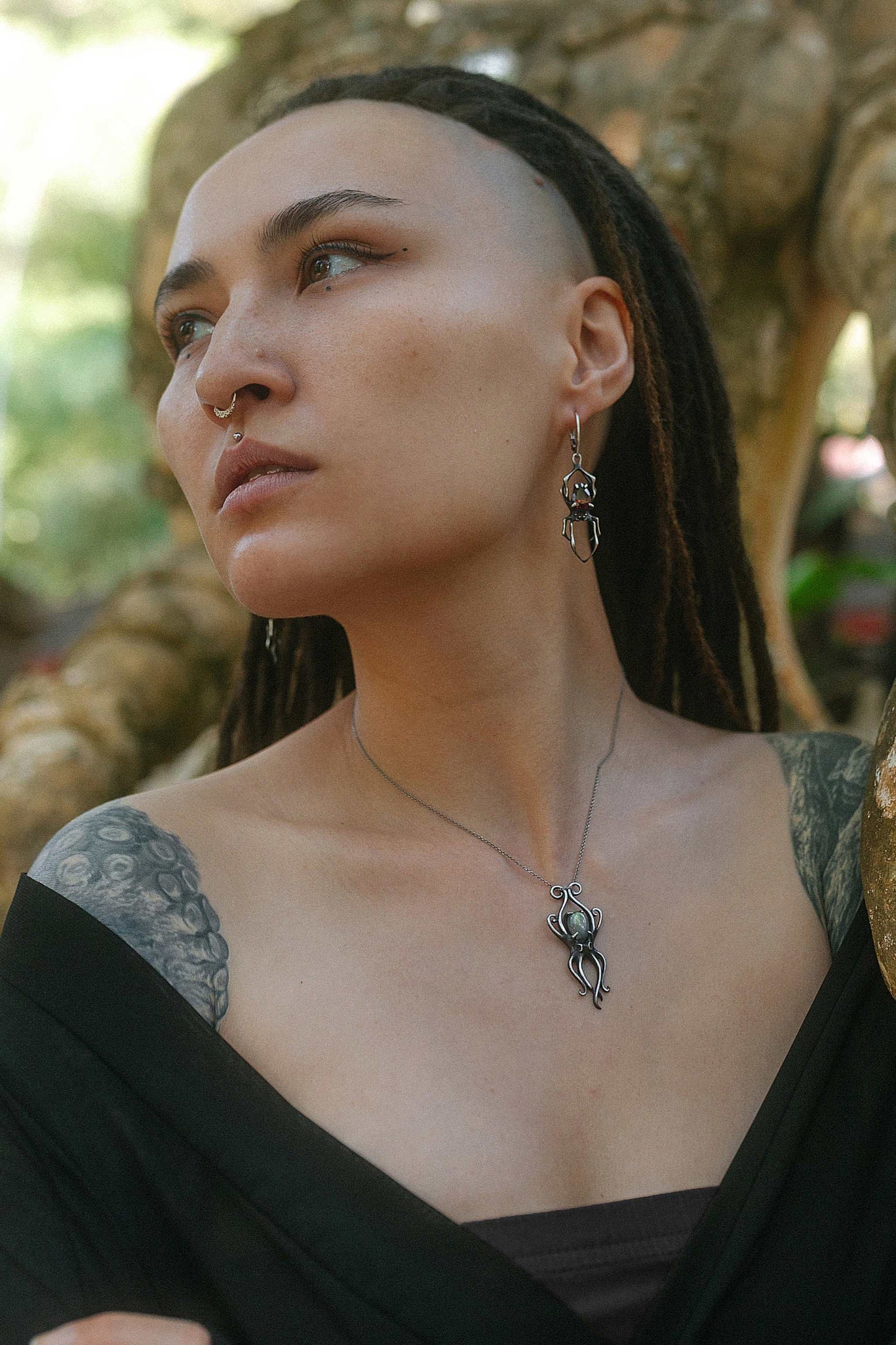 Exotic model with dreadlocks in nature setting wearing silver octopus necklace and Spider earrings