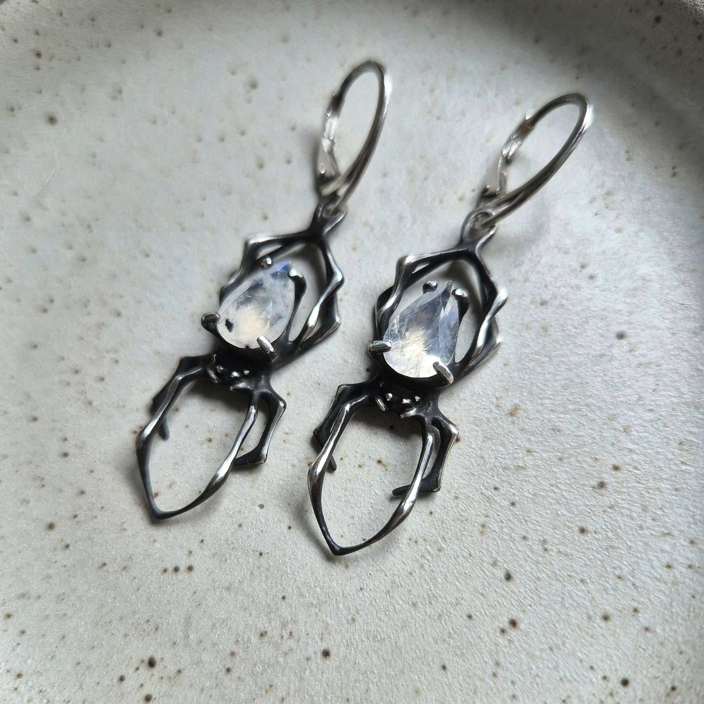 Studio photo of matching silver Spider earrings with sculptural design