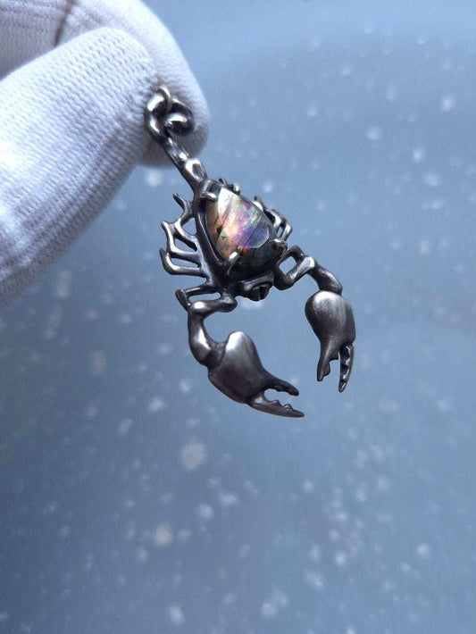 Detailed view of a silver Scorpion necklace with labradorite, glimmering gently in soft light.