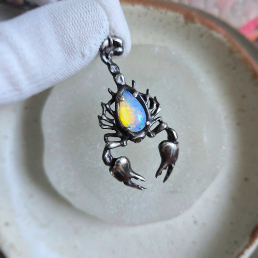 Handmade silver Scorpion necklace featuring a vibrant opal with golden and blue fire, resting on a frosted glass disc