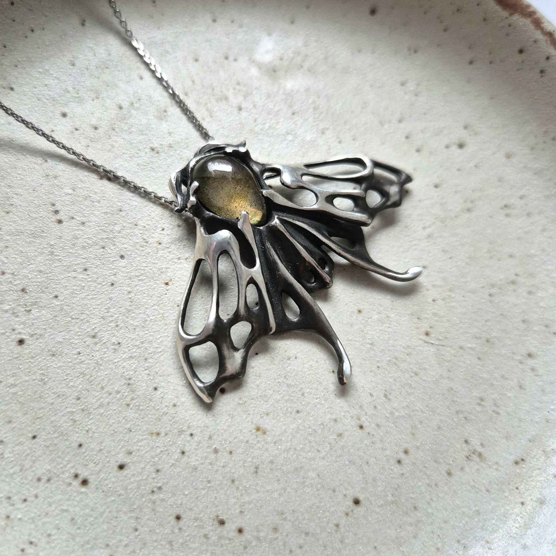 Detailed angled view of silver Moth pendant with fiery golden labradorite gem