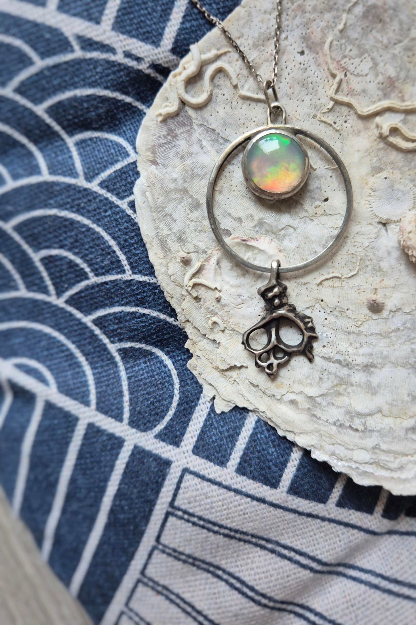 Silver opal necklace photographed on indigo fabric — shimmering opal with sea symbolism