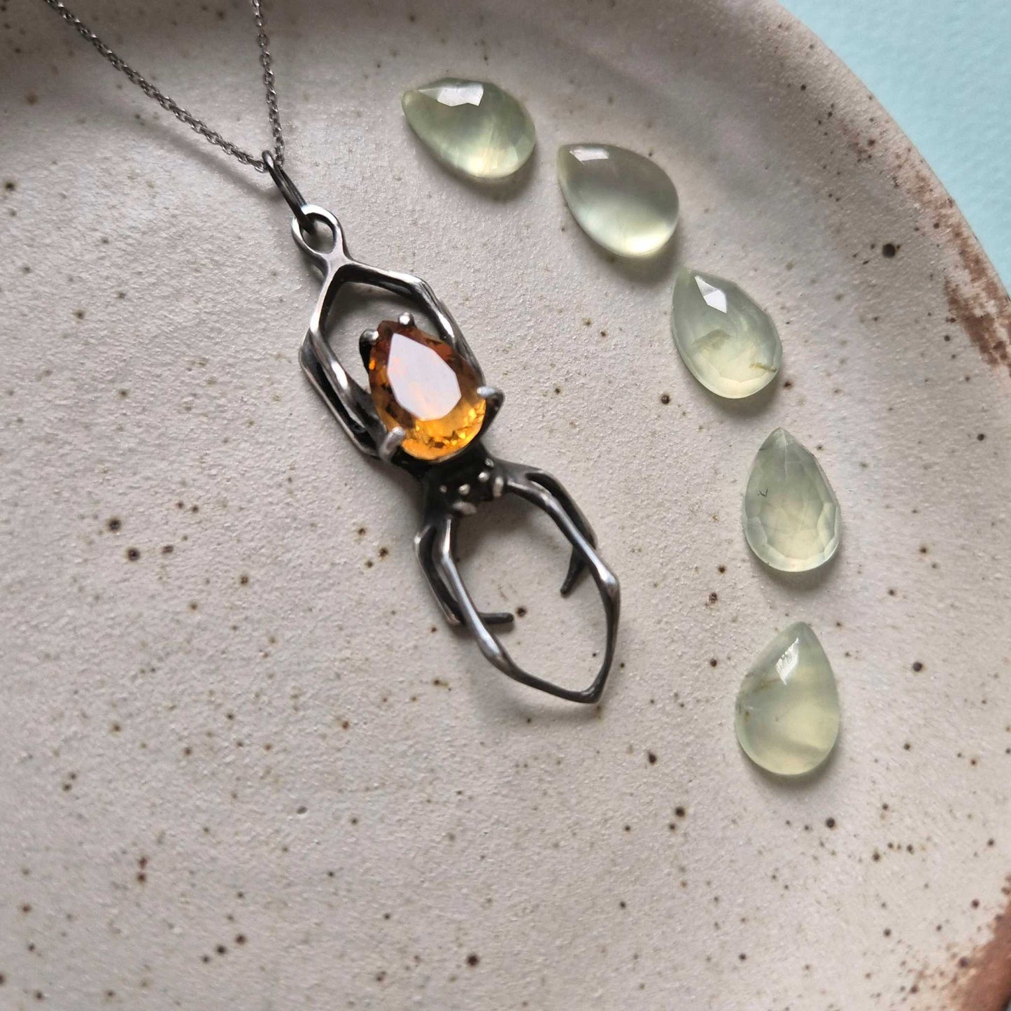 Artistic flat lay of a silver spider necklace with faceted citrine and translucent decorative drops