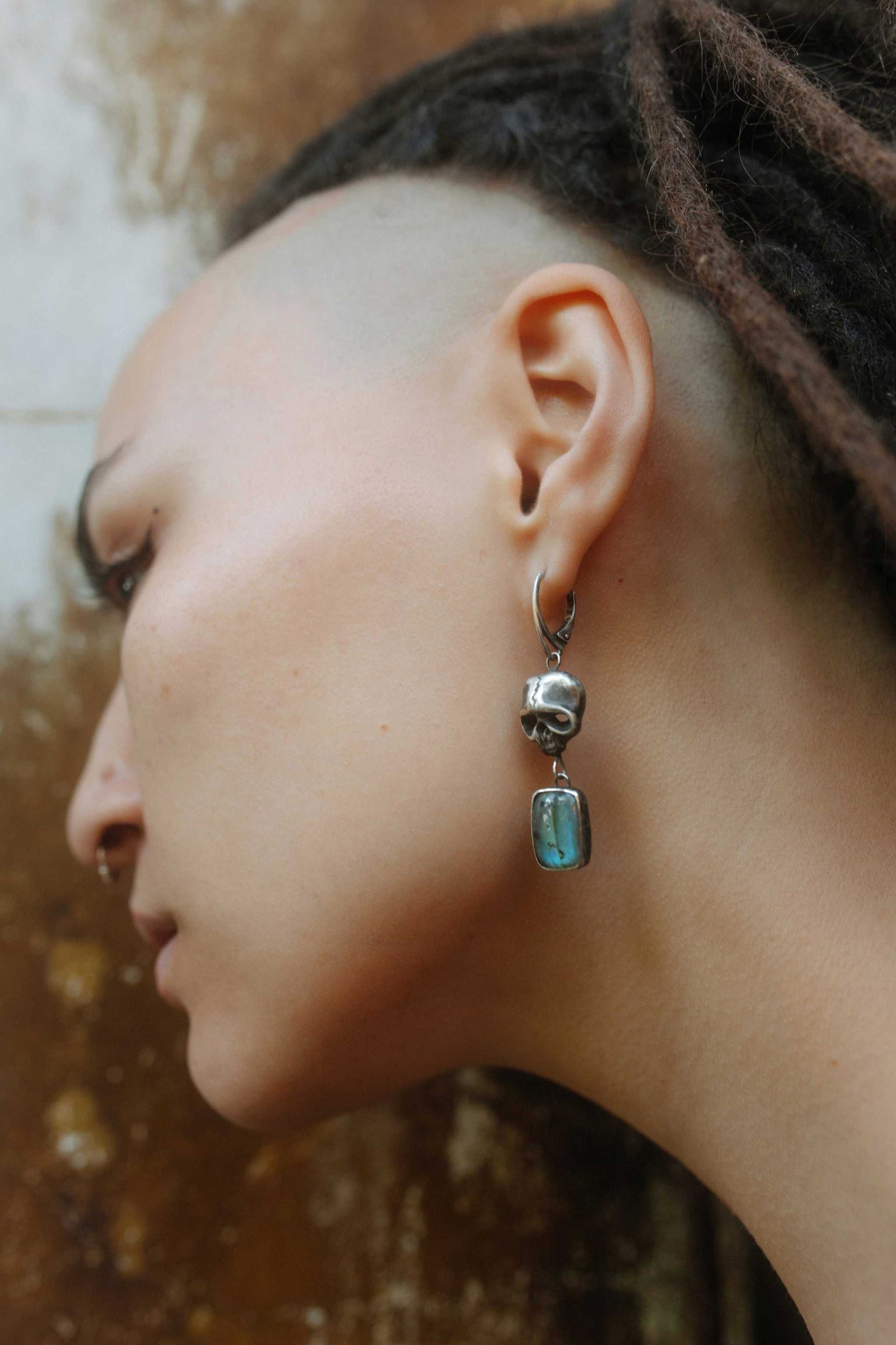Close-up of handmade oxidised silver Skull earrings with blue labradorites, worn by a model in natural boho style