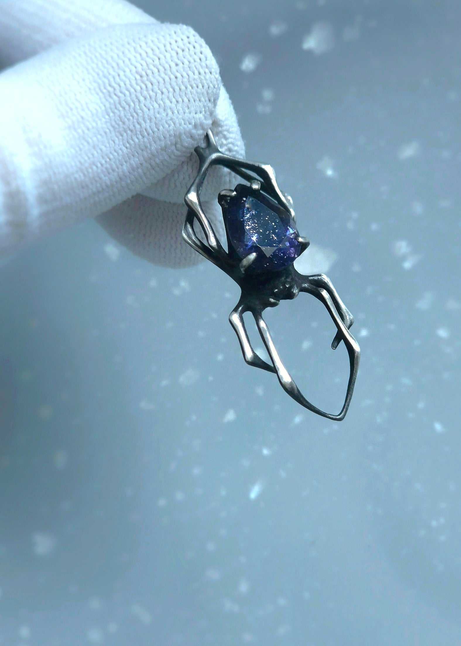 Meaningful spider pendant with iolite sunstone, photographed in hands