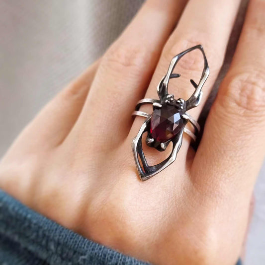 Close-up of silver Spider ring with natural garnet, set against soft lighting to reveal stone facets