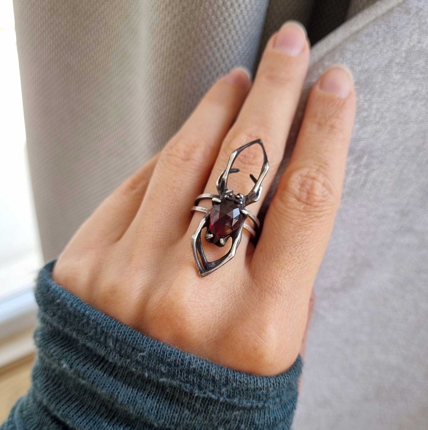 Top view of silver Spider ring on hand, with elongated shape and detailed spider silhouette
