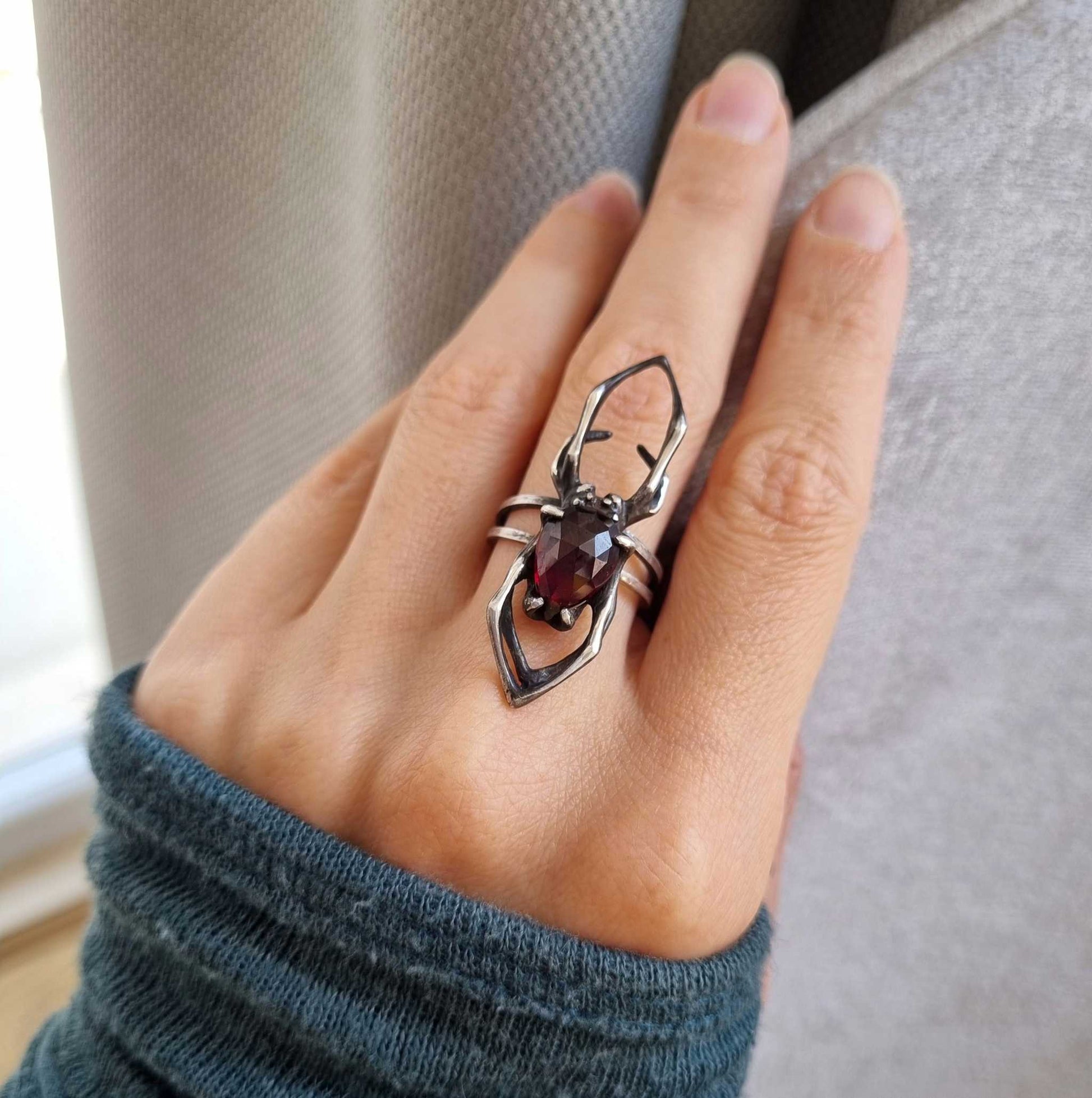 Top view of silver Spider ring on hand, with elongated shape and detailed spider silhouette