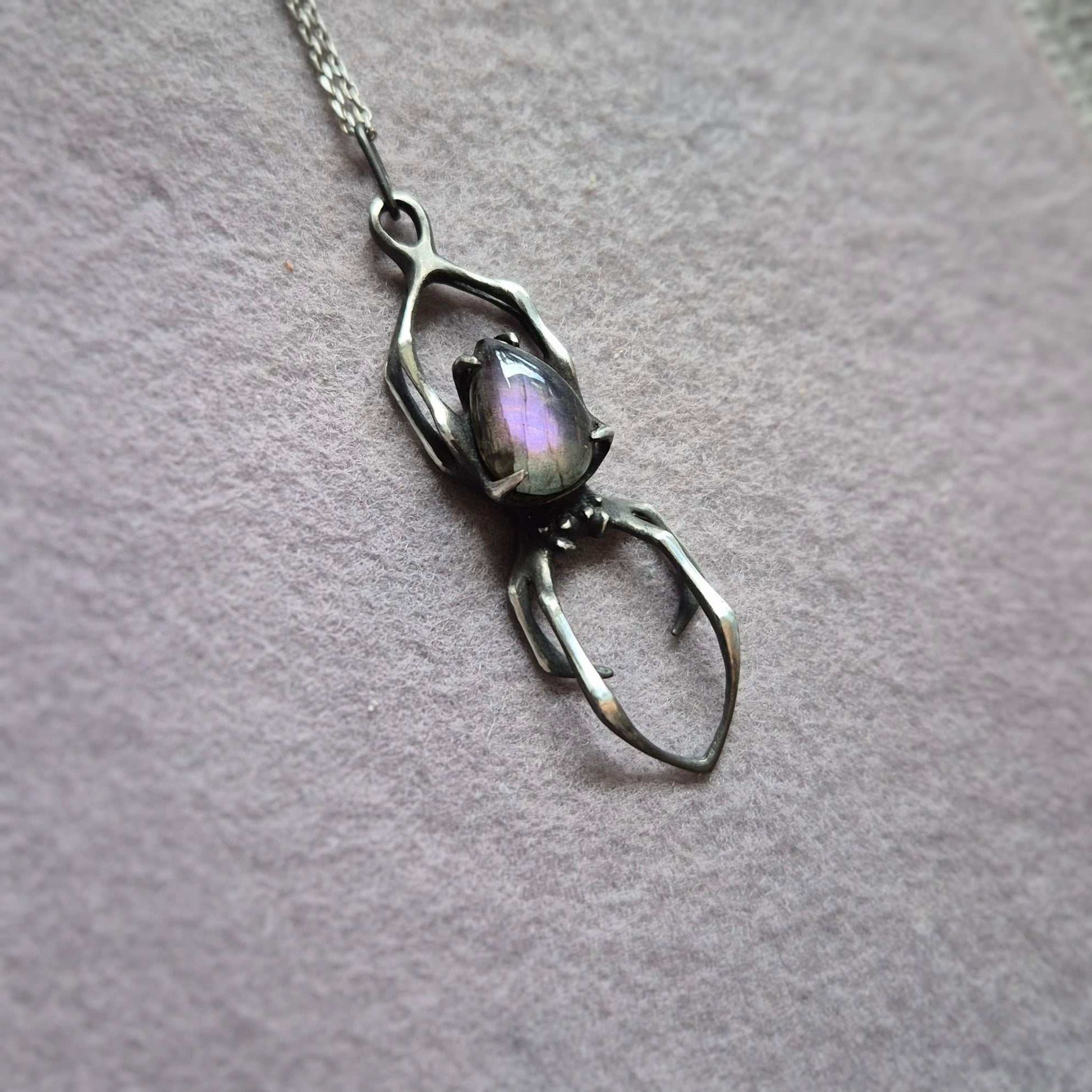 Handmade silver Spider necklace with purple labradorite gemstone on neutral background