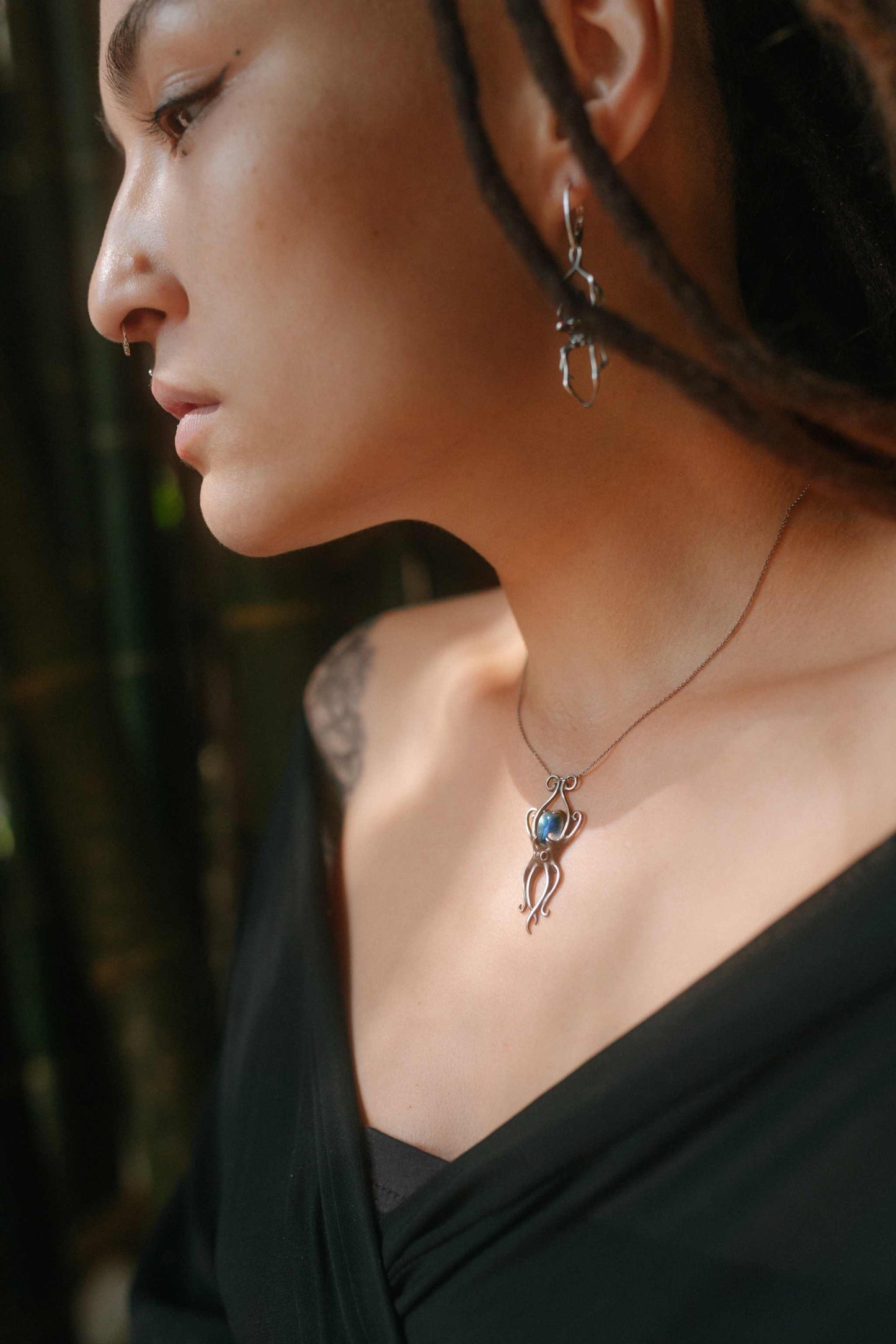Silver Octopus necklace with shimmering blue labradorite worn on a model, side view.
