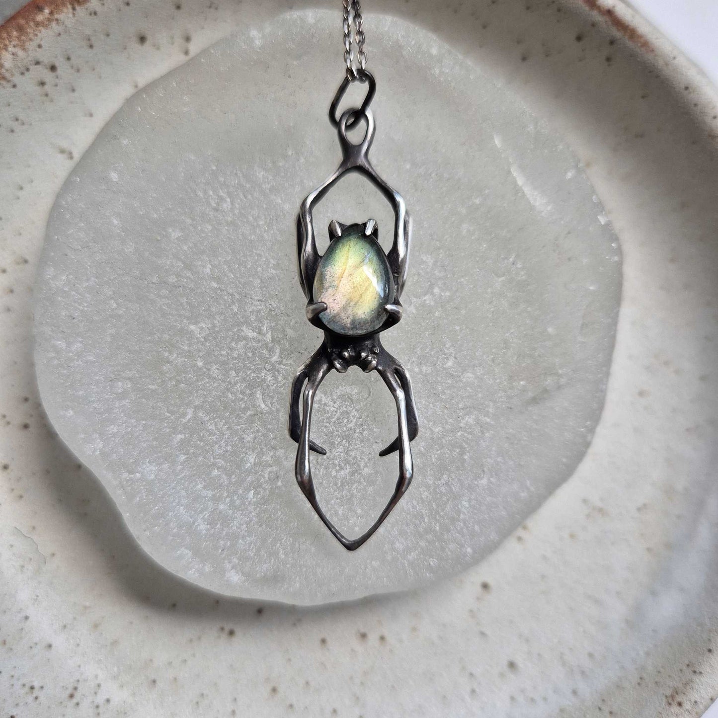 Silver Spider necklace with labradorite gemstone on a neutral background