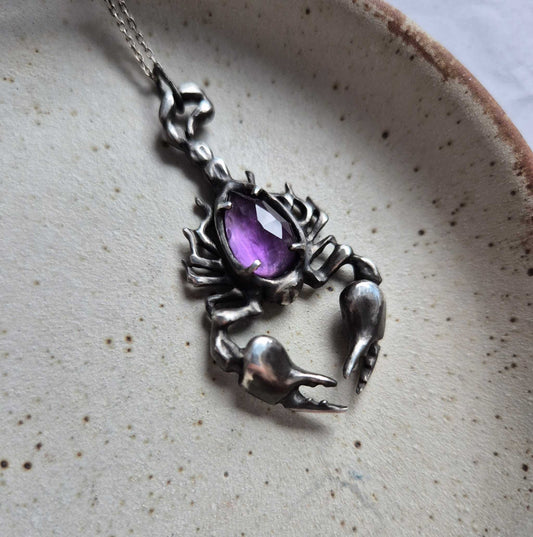 Silver scorpion necklace with rose cut amethyst gemstone on ceramic plate