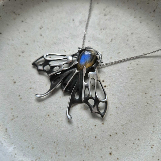 Silver Moth necklace with blue labradorite gemstone on ceramic background