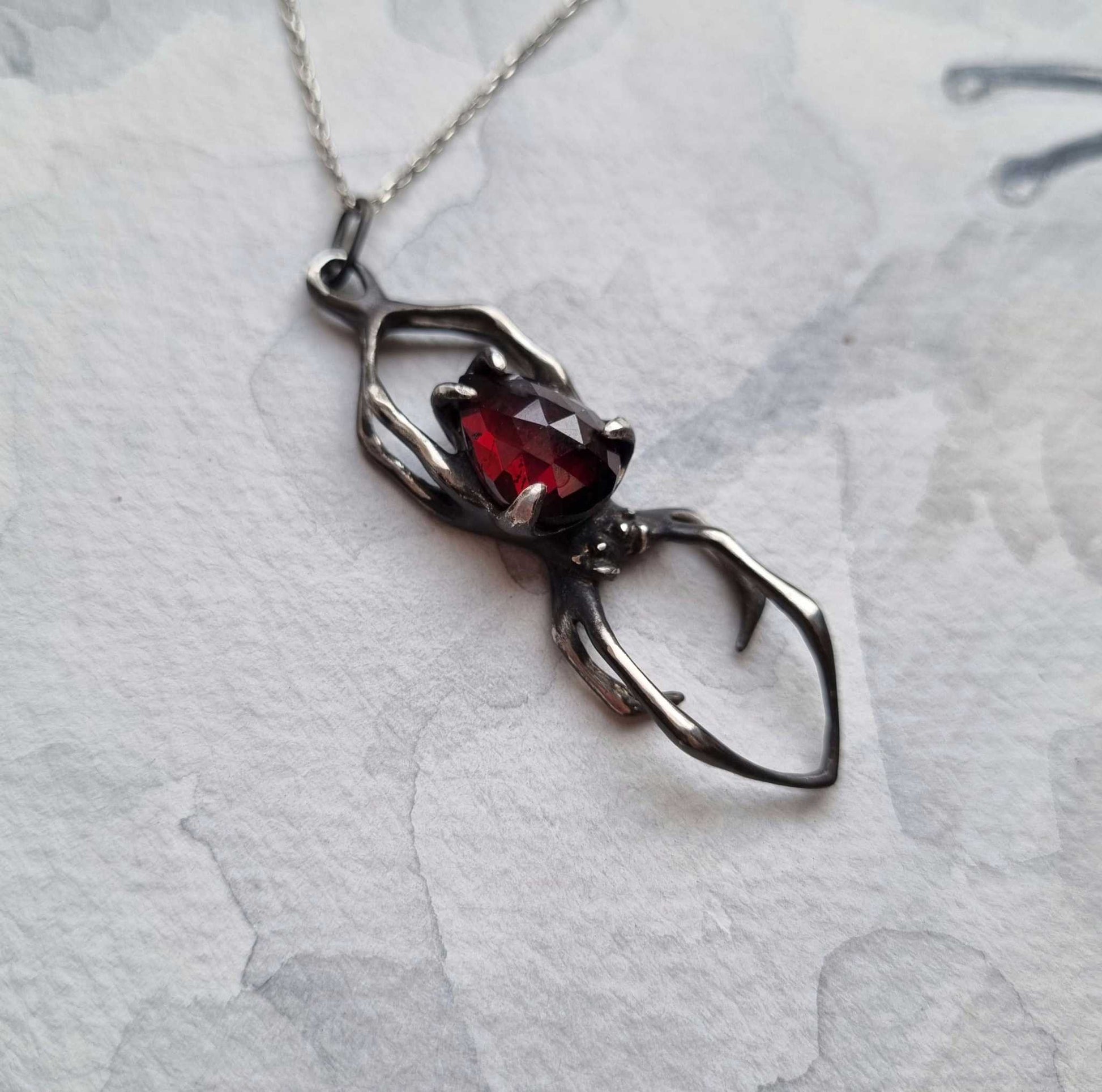 Silver spider necklace with a garnet gemstone  – symbolic handcrafted jewelry
