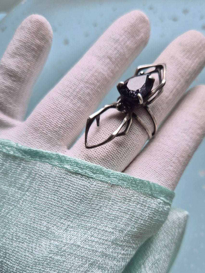 Artisan spider ring with iolite sunstone displayed on gloved hand and mint silk fabric