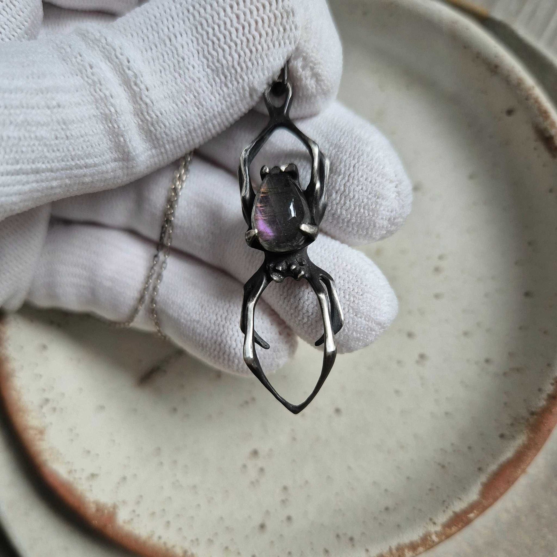 Oxidized silver Spider pendant with blue labradorite in a gloved hand